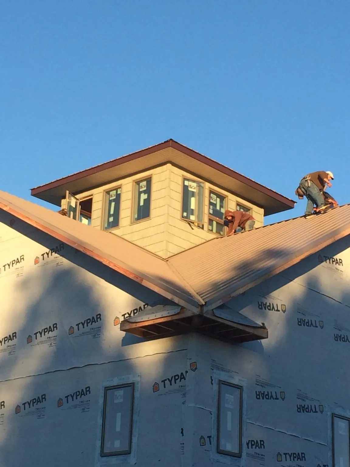 Roofers working around a rooftop cupola on a new metal roof at sunset — Roof Waterproofing in Hudson by Roofing Brothers
